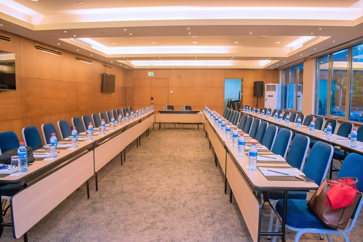 Moderne vergaderruimte met houten tafels opgesteld voor een bijeenkomst.