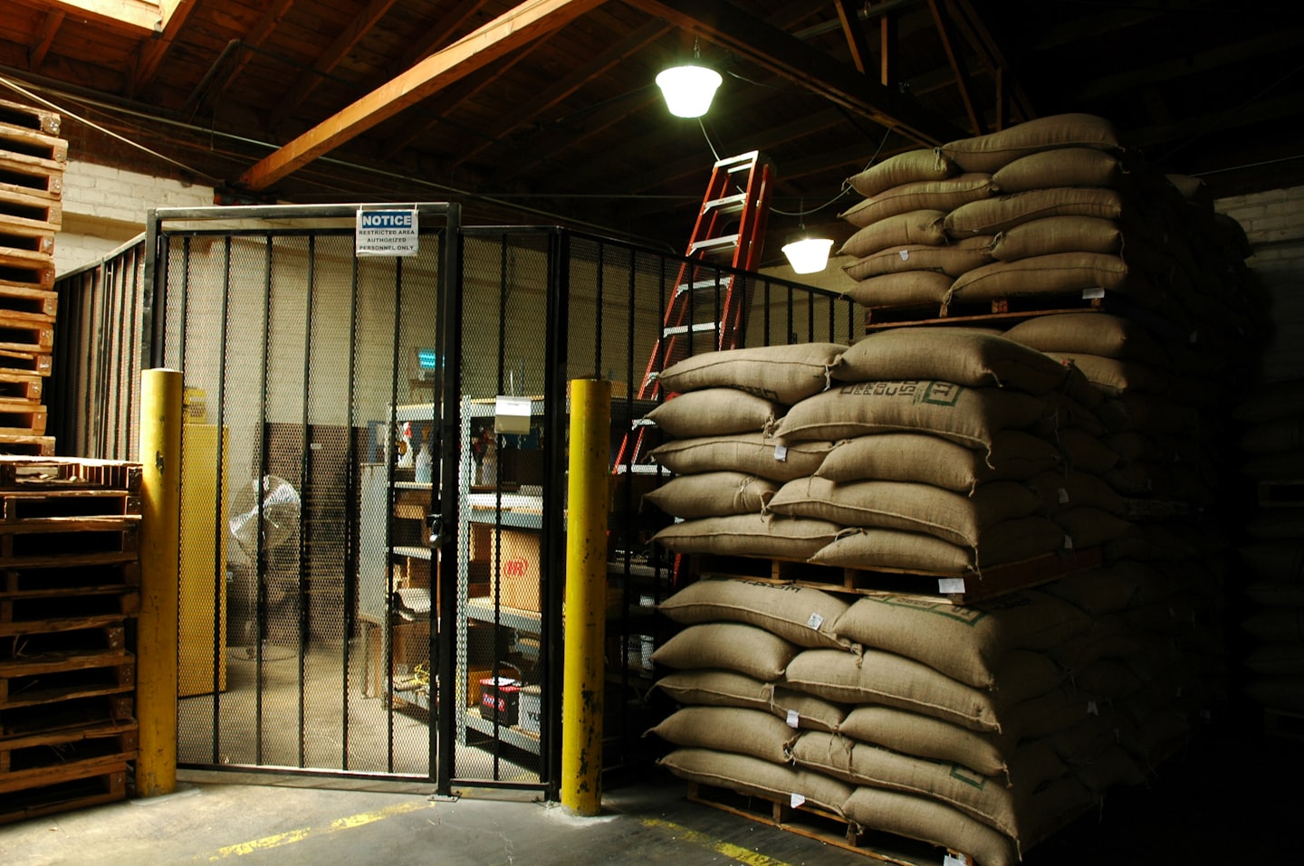 Houten pallets en gestapelde jute zakken in een magazijn.